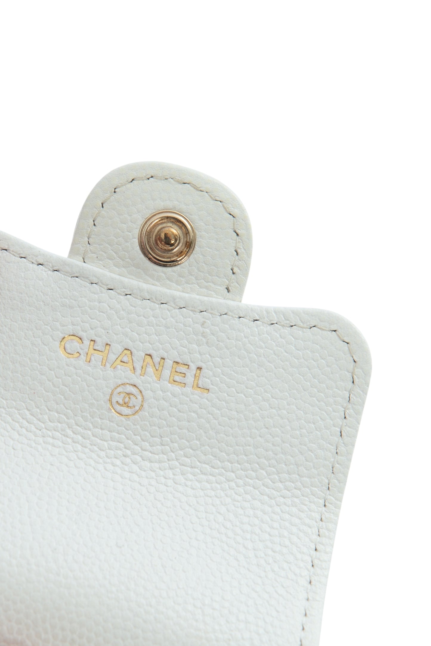 Close-up of a Chanel logo on a white leather product.